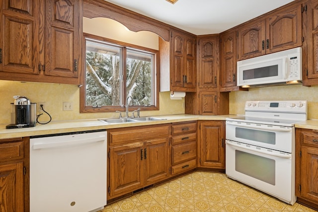 kitchen with white appliances, light floors, a sink, light countertops, and brown cabinets