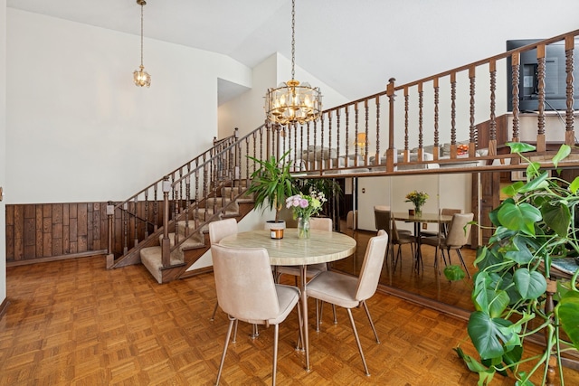 dining room with a notable chandelier, high vaulted ceiling, and stairs