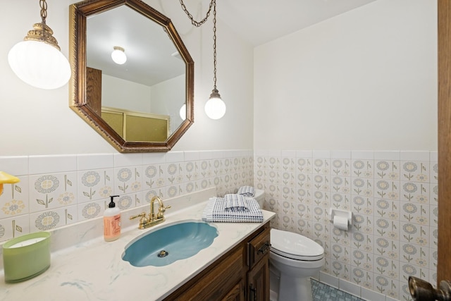 bathroom featuring wainscoting, vanity, toilet, and tile walls