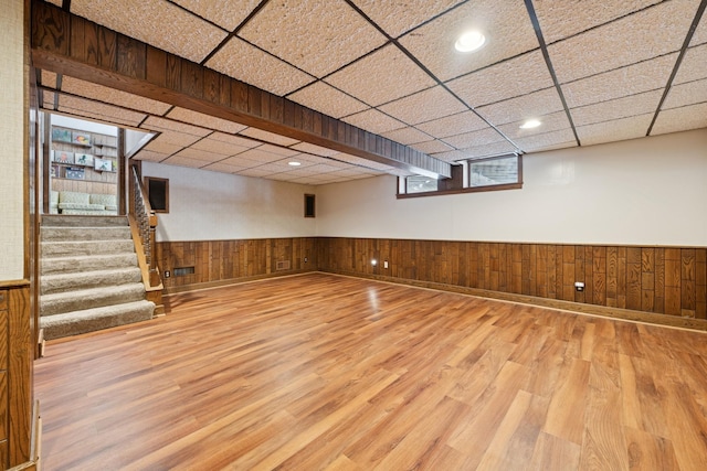 below grade area featuring a paneled ceiling, wood finished floors, and wainscoting