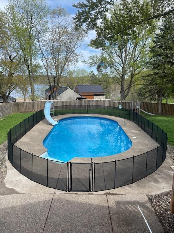 view of swimming pool featuring a fenced in pool, a yard, a water slide, and fence