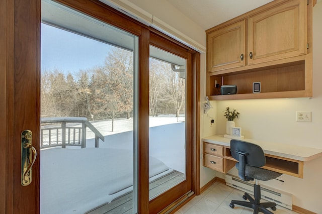 interior space featuring a baseboard heating unit, built in desk, and a wealth of natural light