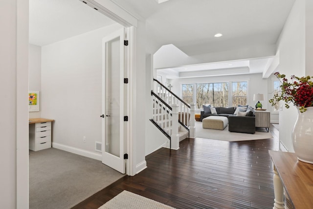 stairs with baseboards, a tray ceiling, wood finished floors, and recessed lighting