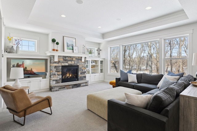 carpeted living area featuring ornamental molding, a tray ceiling, a fireplace, and recessed lighting