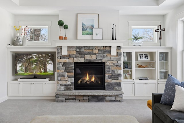 carpeted living room featuring a healthy amount of sunlight and a stone fireplace