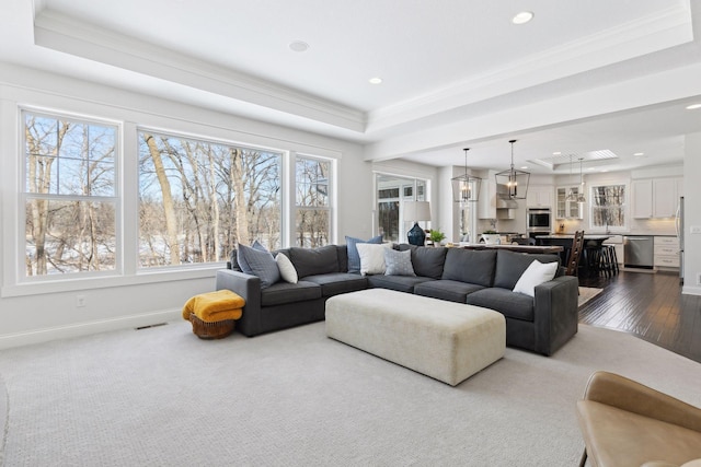 living area featuring recessed lighting, a raised ceiling, visible vents, ornamental molding, and baseboards