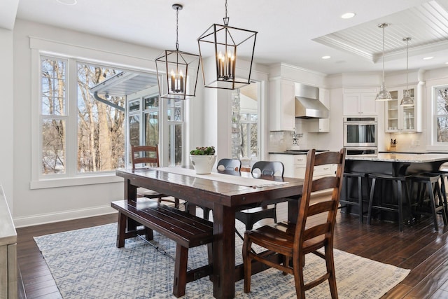 dining space with recessed lighting, a raised ceiling, dark wood finished floors, and baseboards
