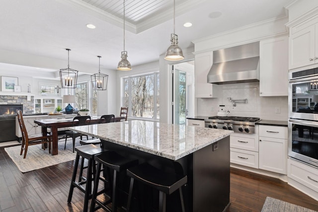 kitchen featuring dark wood-style floors, wall chimney exhaust hood, appliances with stainless steel finishes, and backsplash