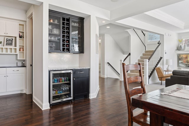 bar featuring a bar, wine cooler, dark wood-style flooring, and backsplash