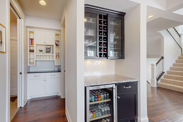 bar featuring wine cooler, stairway, dark wood finished floors, and a dry bar