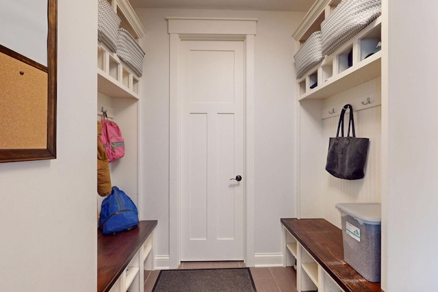 mudroom with dark tile patterned floors and baseboards