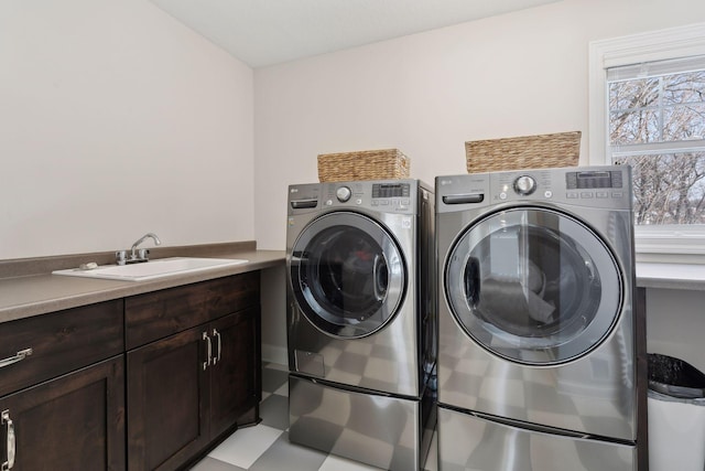 laundry room featuring cabinet space, light floors, a sink, and independent washer and dryer