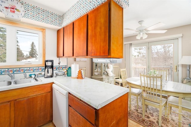 kitchen featuring sink, kitchen peninsula, ceiling fan, and white dishwasher