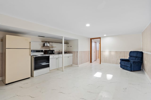 kitchen with wooden walls, white cabinets, electric stove, and white fridge