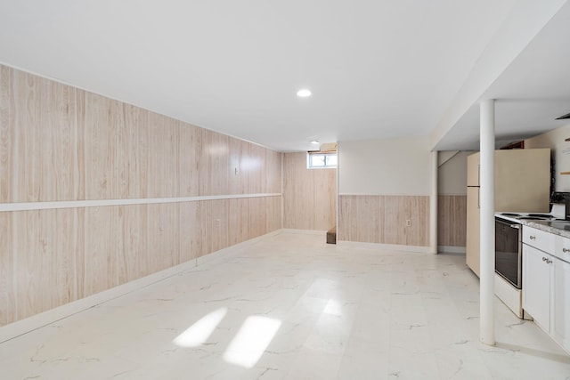 basement featuring white refrigerator and wooden walls