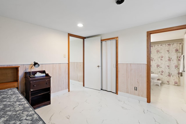 bedroom featuring connected bathroom and wooden walls