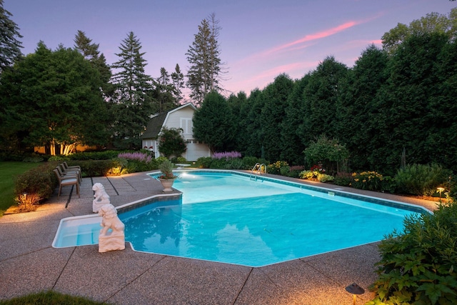 pool at dusk featuring a patio