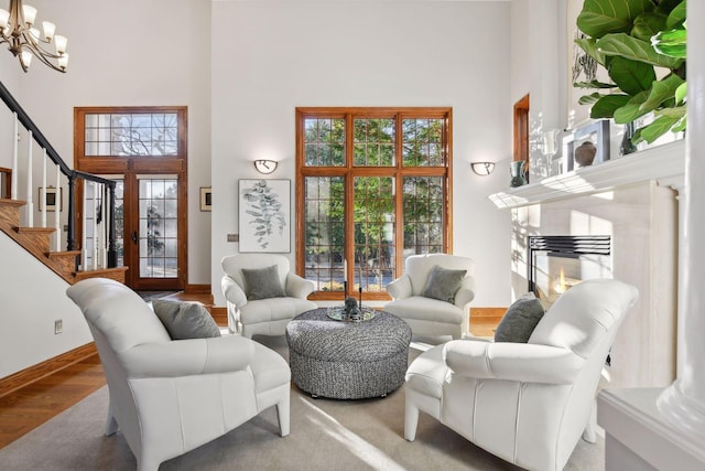 living room with hardwood / wood-style floors, a chandelier, a towering ceiling, and a premium fireplace