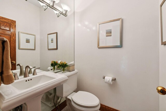 bathroom featuring sink, an inviting chandelier, and toilet