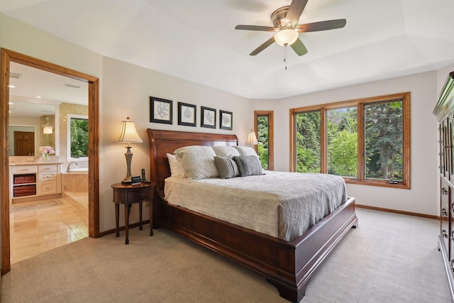 bedroom featuring connected bathroom, ceiling fan, a raised ceiling, and light colored carpet