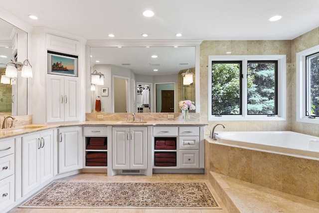 bathroom featuring a relaxing tiled tub and vanity