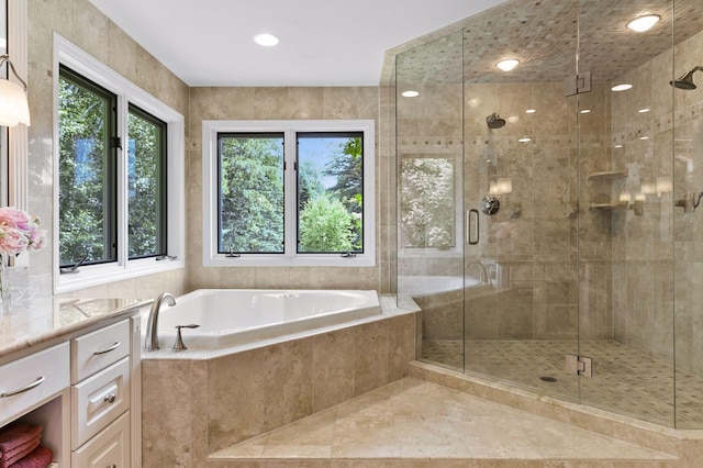 bathroom featuring independent shower and bath, plenty of natural light, and vanity