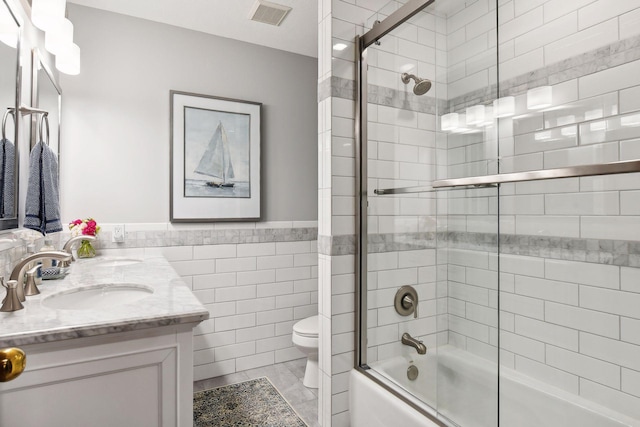 full bathroom with toilet, bath / shower combo with glass door, tile walls, tile patterned floors, and vanity