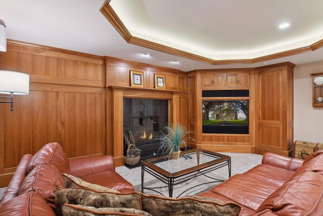 living room with crown molding, a raised ceiling, and wooden walls