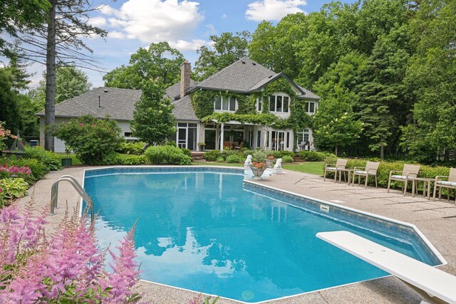 view of pool with a diving board and a patio