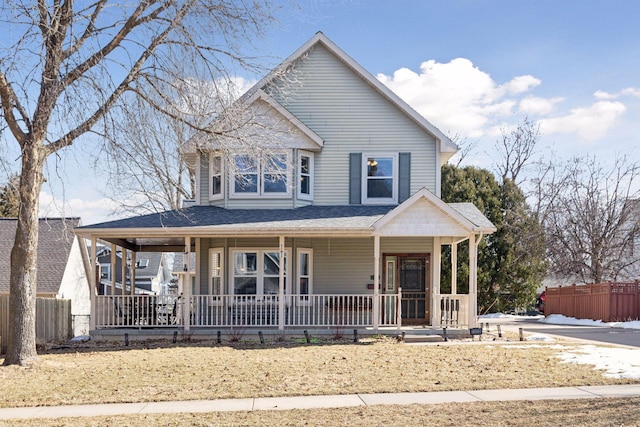 view of front of property featuring covered porch, a shingled roof, and fence