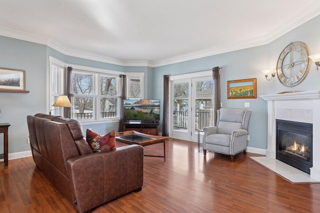 living area with baseboards, wood finished floors, a high end fireplace, and ornamental molding