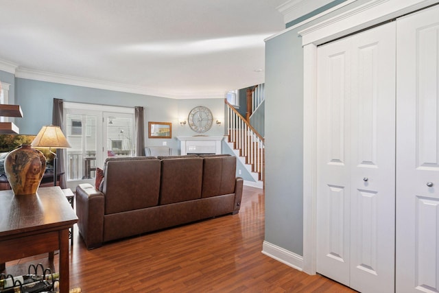 living area featuring ornamental molding, wood finished floors, a fireplace, baseboards, and stairs