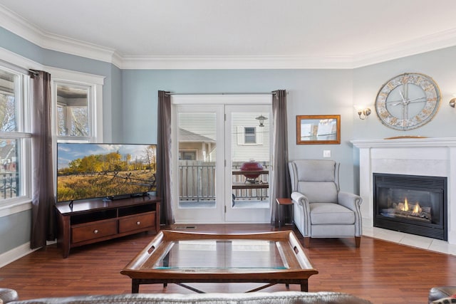 living room featuring ornamental molding, wood finished floors, baseboards, and a tile fireplace