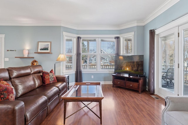 living area with baseboards, wood finished floors, visible vents, and ornamental molding