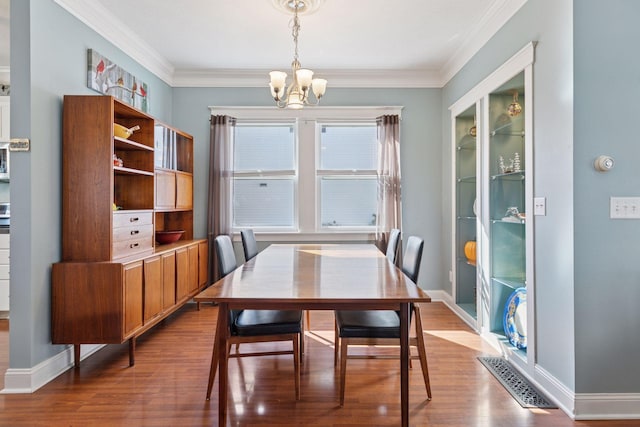 dining space featuring ornamental molding, wood finished floors, baseboards, and a chandelier