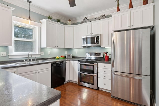 kitchen featuring dark countertops, ornamental molding, stainless steel appliances, and a sink