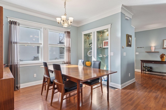 dining space with baseboards, a notable chandelier, wood finished floors, and crown molding