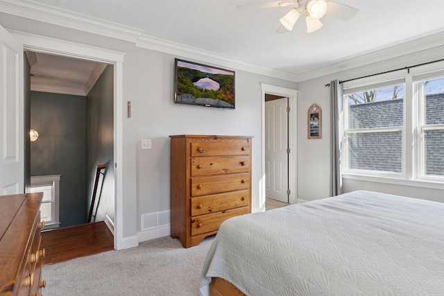 bedroom featuring visible vents, ornamental molding, a ceiling fan, baseboards, and light colored carpet