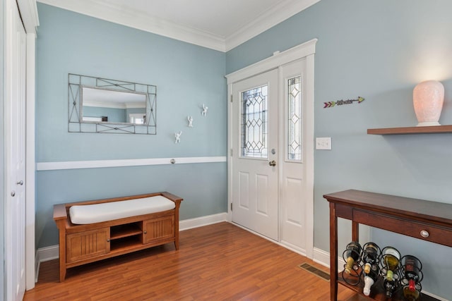 entryway featuring baseboards, wood finished floors, visible vents, and ornamental molding