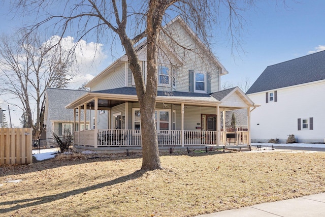 country-style home with a porch and fence