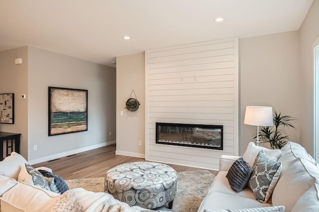 living room with a large fireplace, wood finished floors, recessed lighting, and baseboards