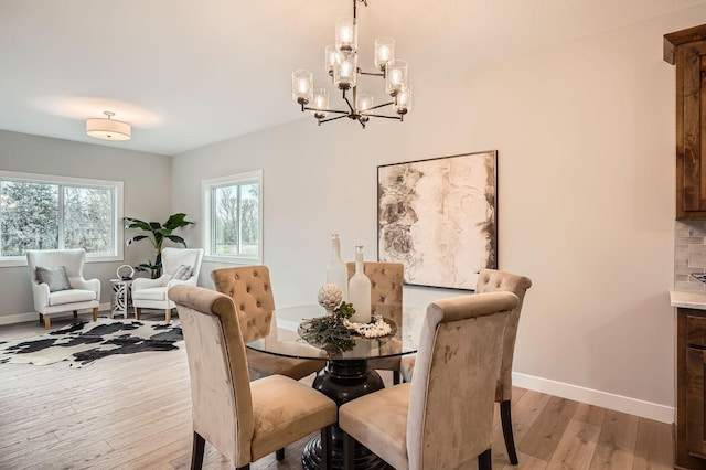 dining area featuring baseboards, light wood-type flooring, and a notable chandelier