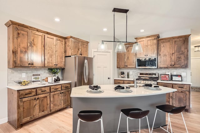kitchen with tasteful backsplash, light wood finished floors, appliances with stainless steel finishes, and light countertops