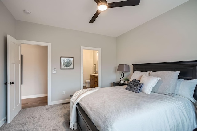 bedroom with ensuite bathroom, a ceiling fan, light colored carpet, and baseboards