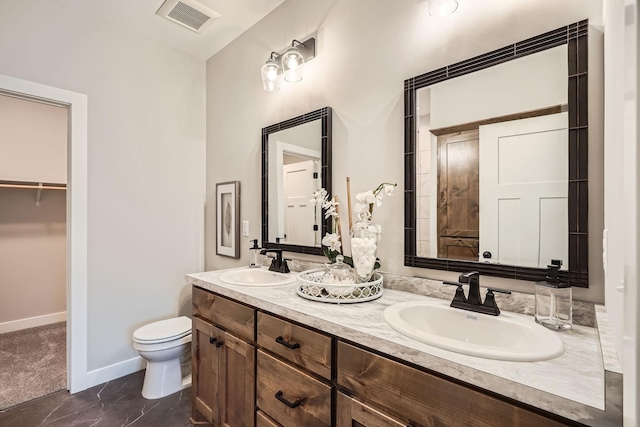 bathroom featuring visible vents, toilet, double vanity, and a sink