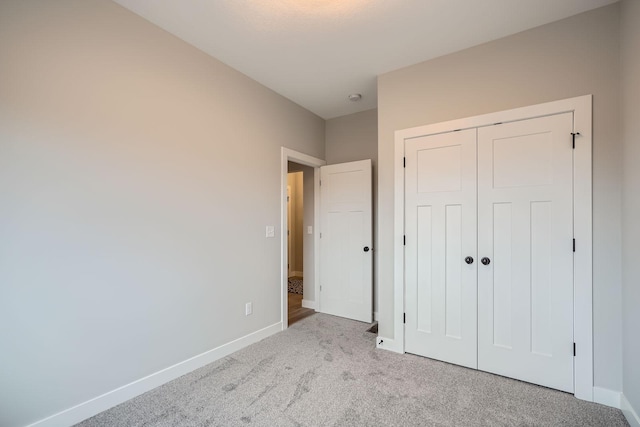unfurnished bedroom featuring a closet, carpet, and baseboards