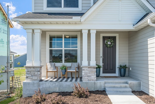 property entrance featuring covered porch and roof with shingles