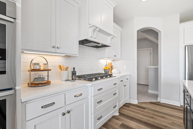 kitchen featuring dark wood-style floors, light countertops, backsplash, and stainless steel gas stovetop