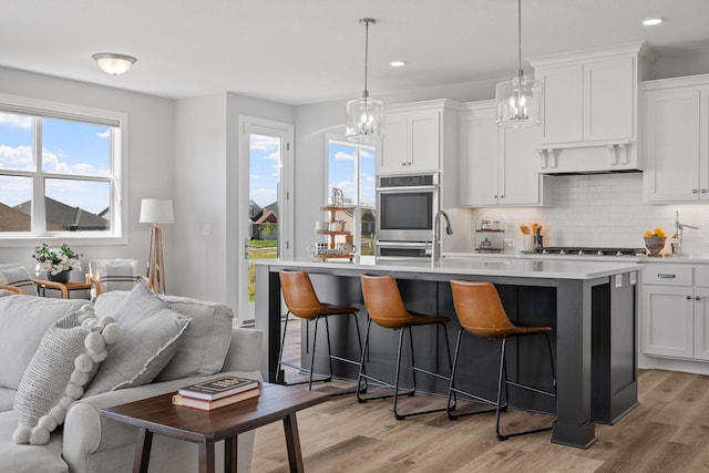 kitchen featuring light wood-type flooring, a breakfast bar, open floor plan, and backsplash