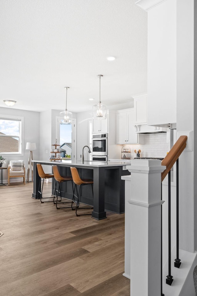 kitchen with white cabinets, light wood-style floors, a breakfast bar, and light countertops